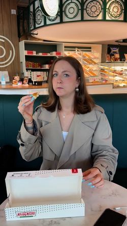 Une cliente dégustant un doughnut dans le café Krispy Kreme, décor moderne et ambiance conviviale.