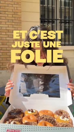 Boîte ouverte avec plusieurs doughnuts variés devant une personne à l'extérieur d'un café.