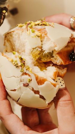 Beignet glacé blanc garni de pistaches, tenu à la main dans un café Krispy Kreme à Vélizy 2.