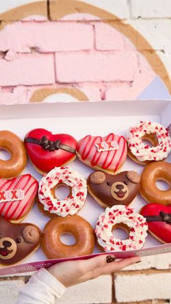 Une boîte de beignets décorés pour une occasion spéciale, incluant des thèmes d'amour et d'ours.