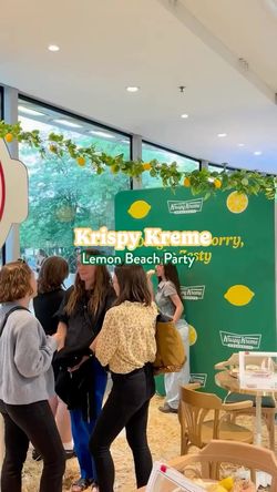 Intérieur lumineux d'un Krispy Kreme avec décorations citron, plusieurs personnes discutant dans un espace de restauration.