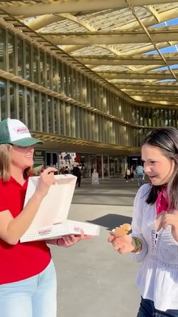 Deux personnes dégustant des doughnuts à l'extérieur sous une grande verrière près du Krispy Kreme - CC Passage du Havre.