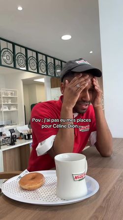 Un employé de Krispy Kreme à Paris sert un café et un doughnut sur un plateau dans le café. 