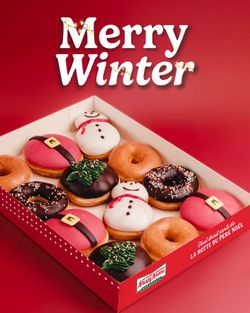 Une boîte de beignets variés de Krispy Kreme, incluant des motifs festifs et traditionnels.