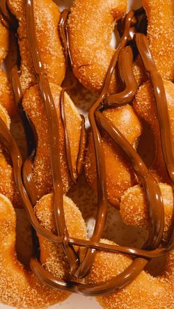 Doughnuts enrobés de sucre et nappés de chocolat, offrant un dessert sucré et gourmand chez Krispy Kreme - CC Qwartz.