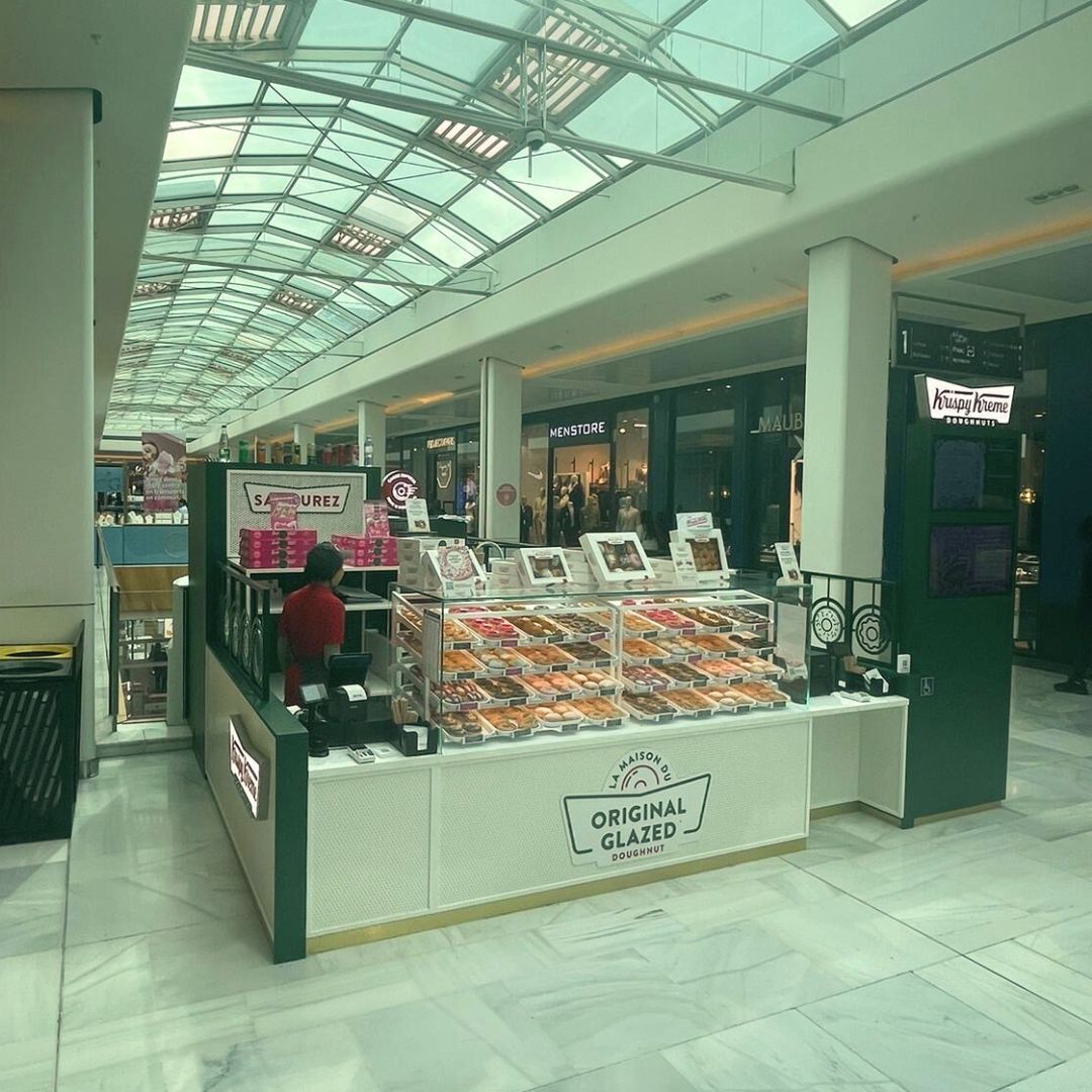 Bright café area featuring a display of various doughnuts and sweets, available for takeaway.