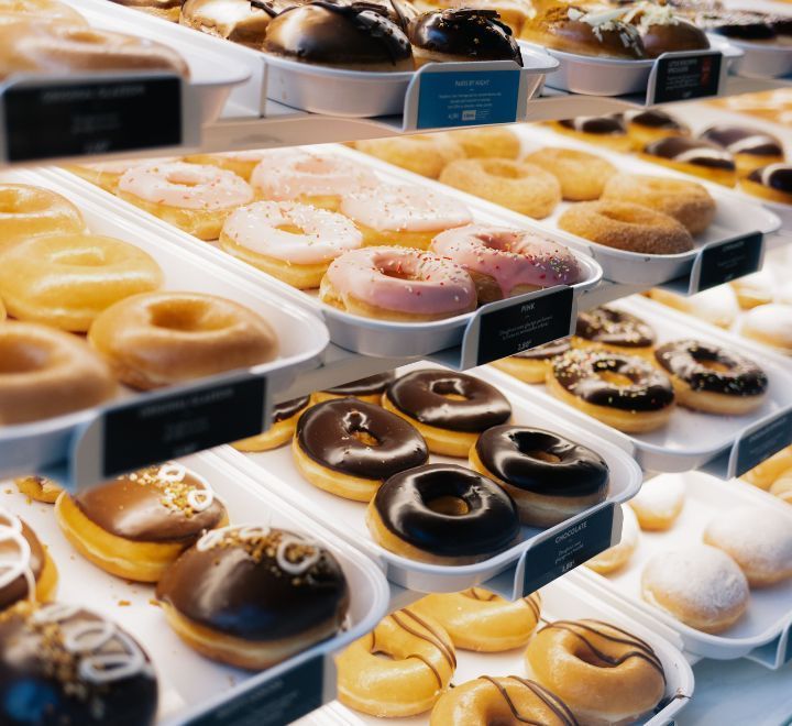 Variété de doughnuts glacés et fourrés exposés sur plusieurs étagères dans la pâtisserie Krispy Kreme.