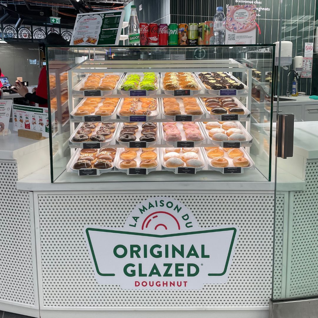 Vitrine avec une sélection variée de doughnuts, idéale pour un petit-déjeuner ou un dessert.