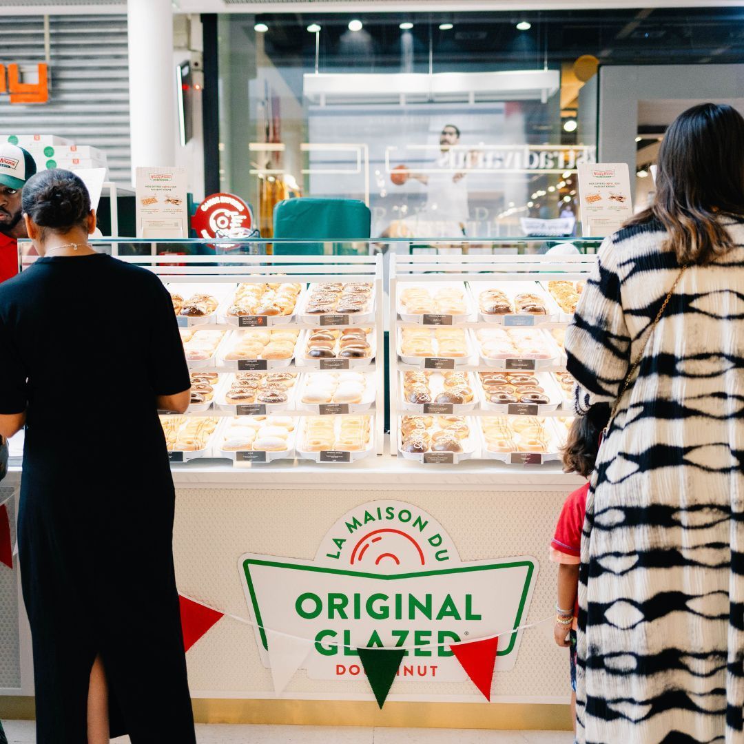 Rétro de la vitrine avec une sélection de doughnuts variés dans un café animé.