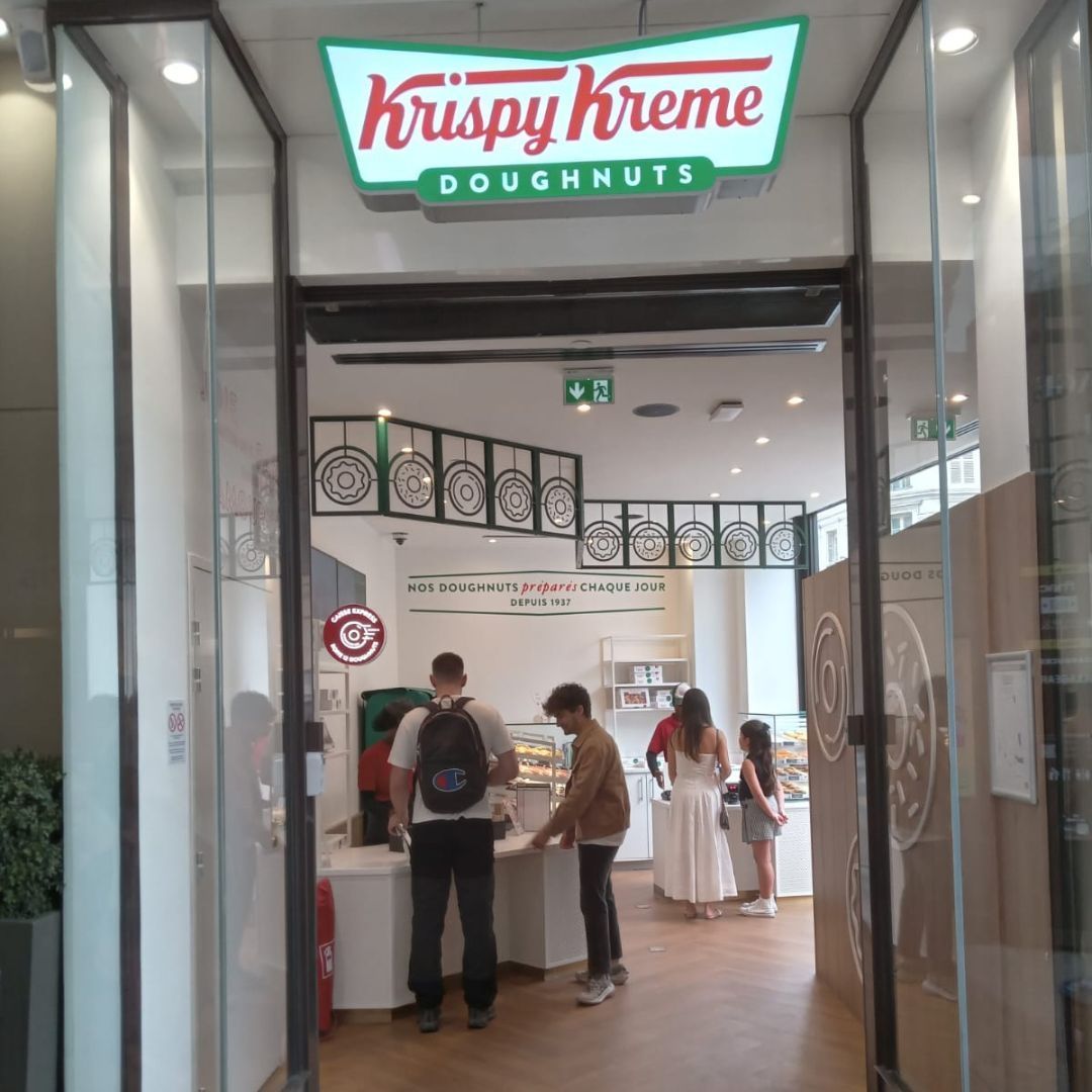 Krispy Kreme store entrance featuring doughnuts and café for breakfast and dessert.