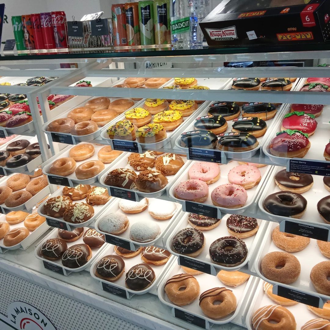 Vitrine de beignets variés, incluant des options au chocolat et au fruit, idéale pour le petit-déjeuner ou le dessert.