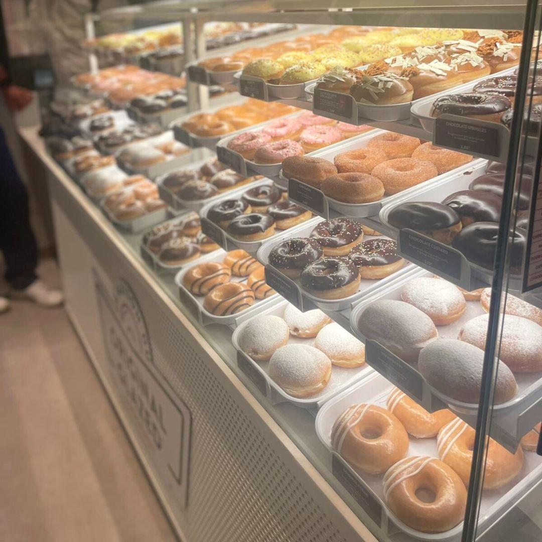 An array of assorted doughnuts displayed in a showcase, featuring various toppings and flavors.