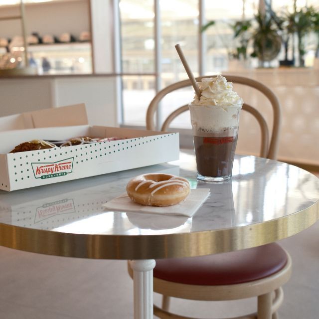 Doughnut sur une table avec boîte Krispy Kreme et boisson café frappé avec crème chantilly dans un café