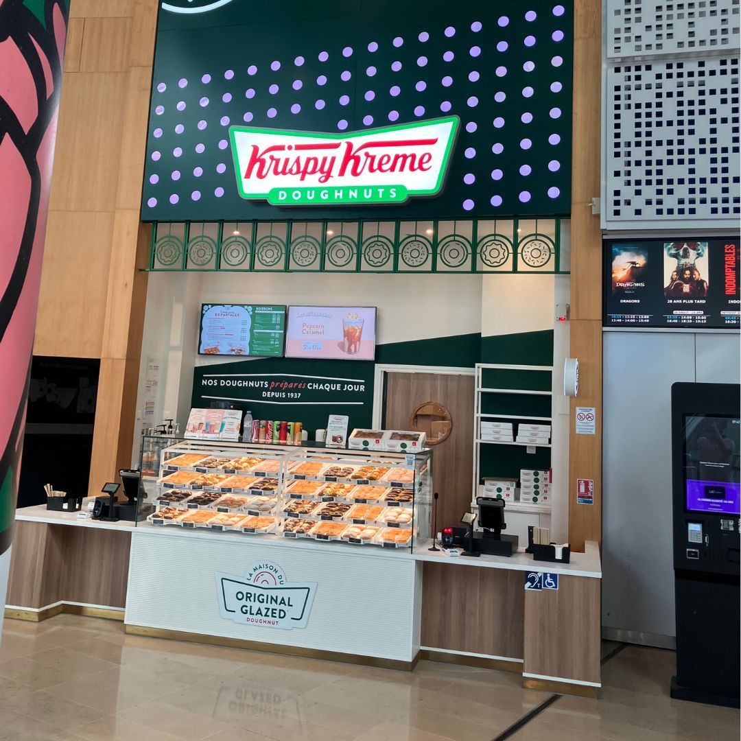 Stand de Krispy Kreme avec un large choix de doughnuts et un café à emporter.