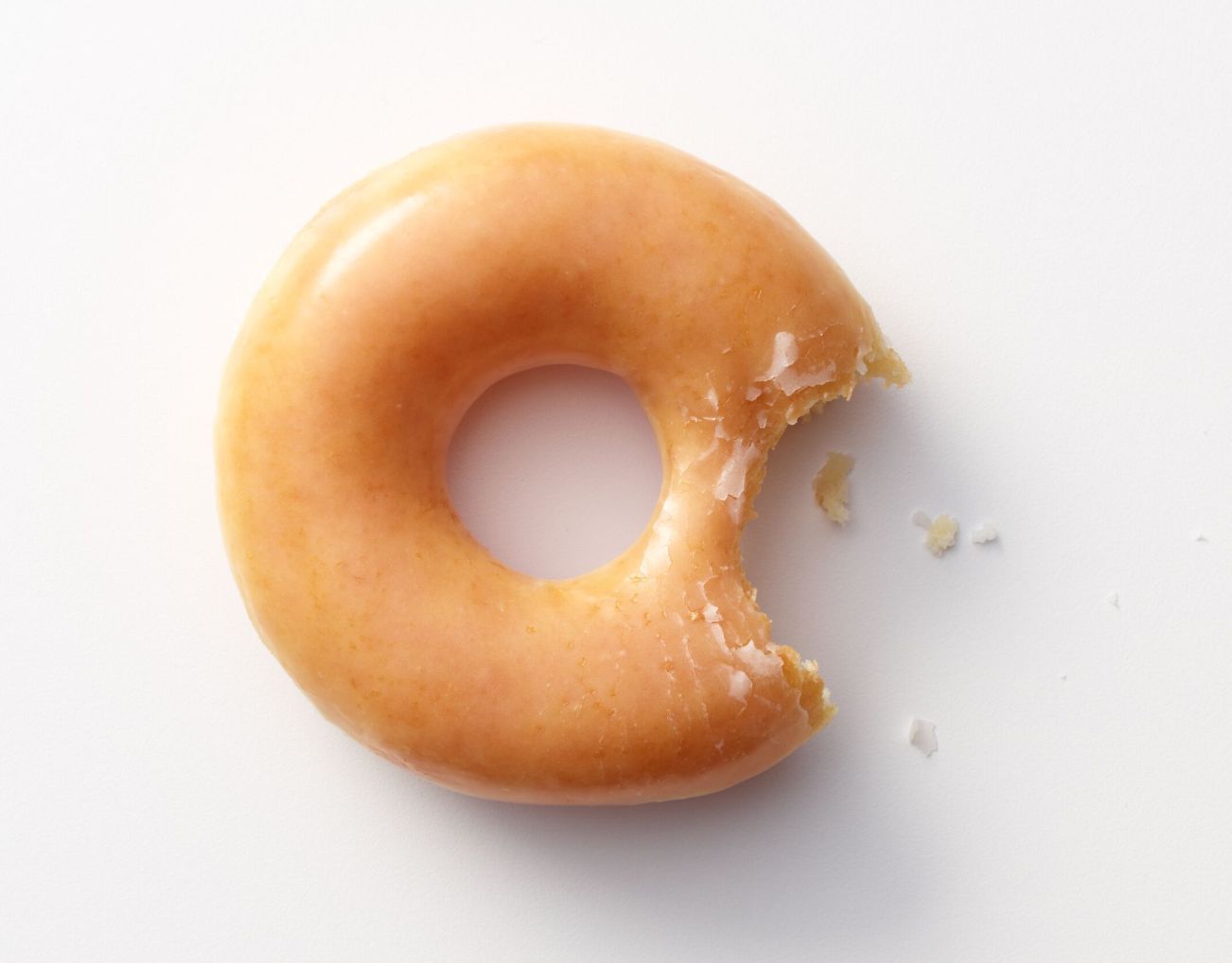 Glazed doughnut with a bite taken out, ideal for breakfast or dessert at Krispy Kreme.
