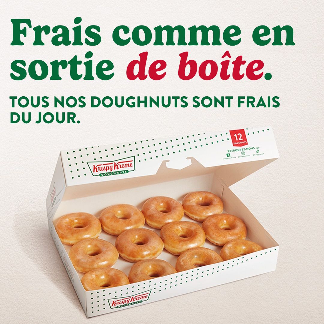 Freshly made doughnuts displayed in a box, available for dessert or breakfast at Krispy Kreme.