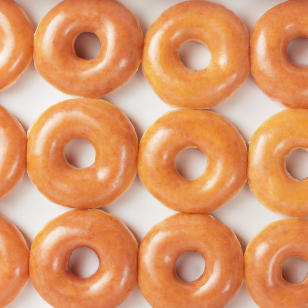Freshly glazed doughnuts arranged in a neat pattern, ideal for dessert or breakfast at Krispy Kreme.
