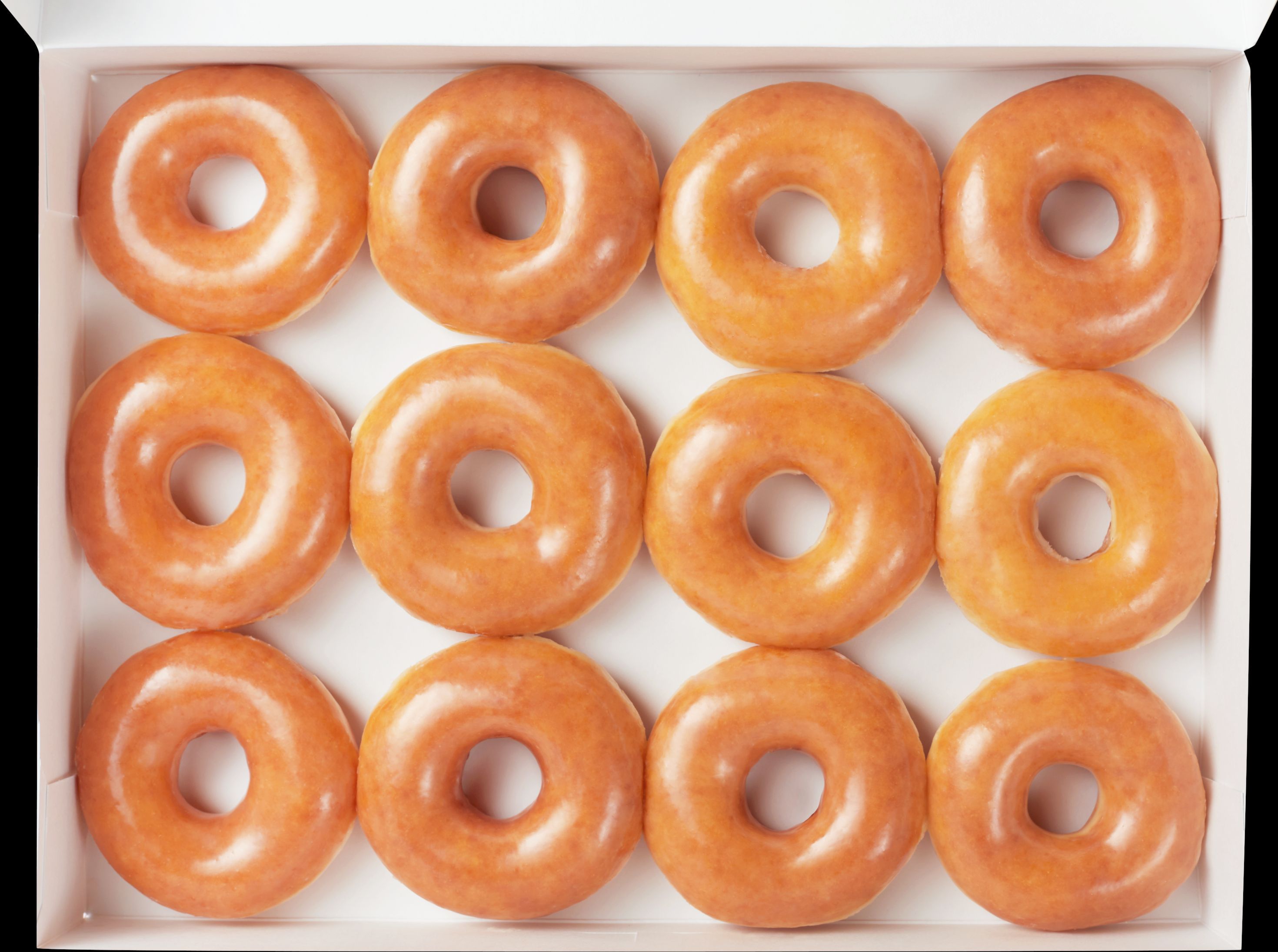 Boîte blanche contenant plusieurs doughnuts ronds et glacés, typiques de Krispy Kreme.