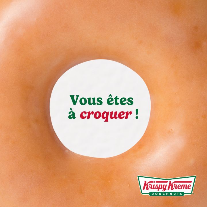 Fresh, glazed doughnut with a smooth surface, showcasing the Krispy Kreme logo and a playful message.