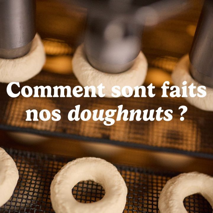Doughnuts fraîchement préparés en cours de cuisson dans une machine à pâtisserie.