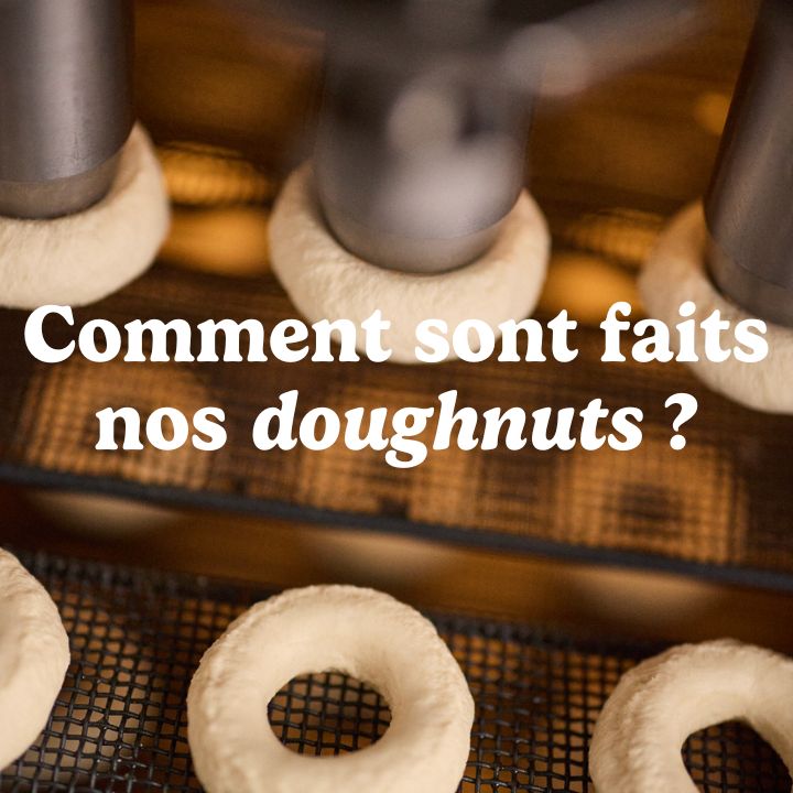Doughnuts en cours de préparation dans une vitrine avec un éclairage chaleureux.