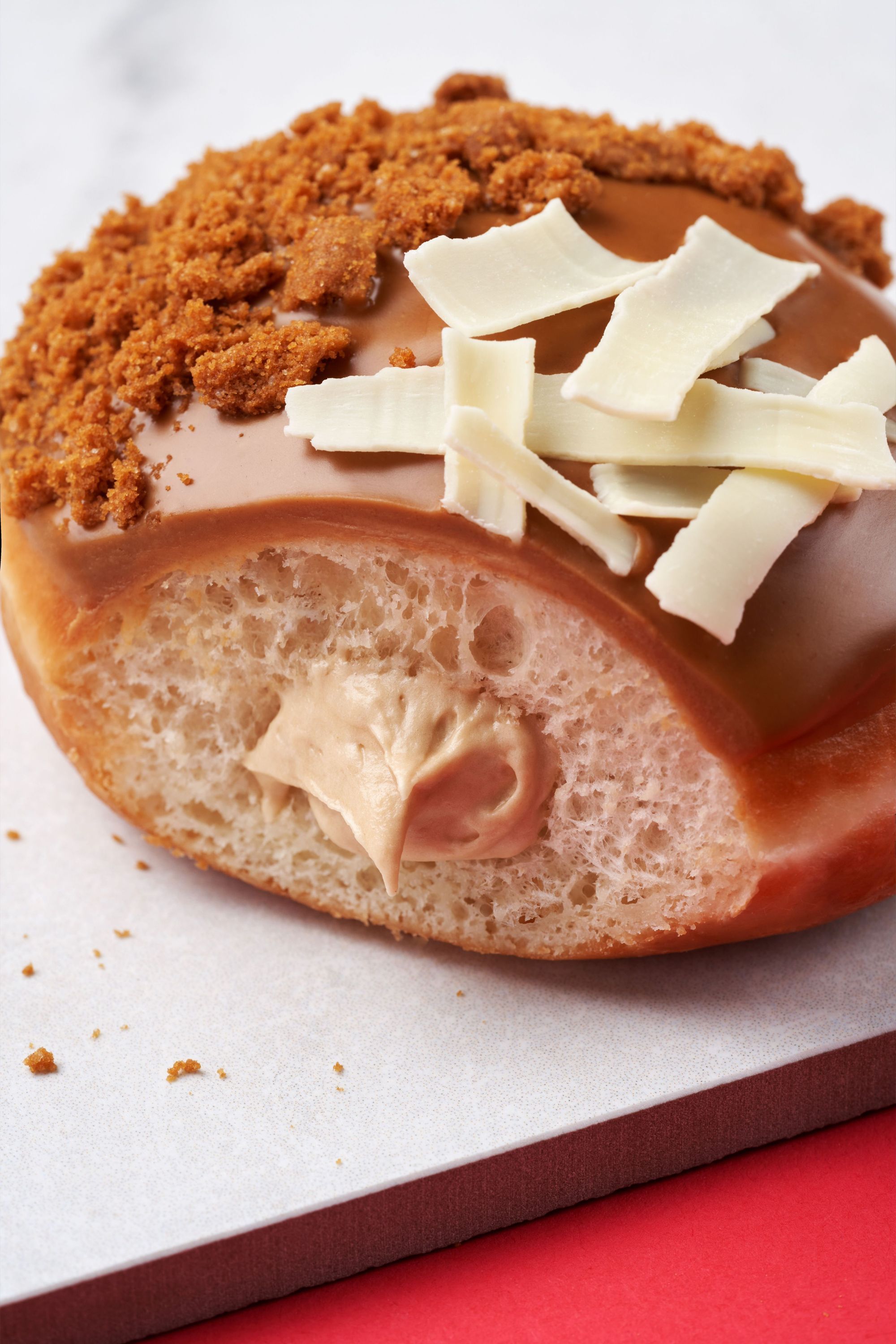 Doughnut fourré à la crème, glacé au caramel avec des copeaux de chocolat blanc et des miettes croustillantes.