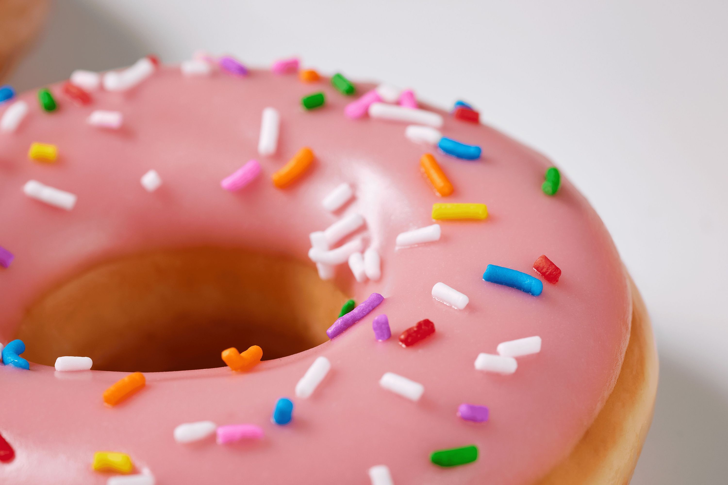 A pink frosted doughnut topped with colorful sprinkles, showcasing a variety of textures.